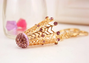 Gros plan d'un porte-clés couronne dorée évidée avec strass violets et design en métal