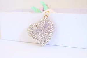 Close-up of golden heart-shaped keychain pendant encrusted with sparkling white rhinestones