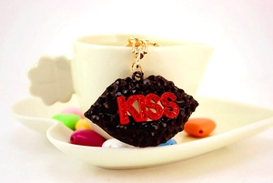 Detail of red KISS lips keychain with black rhinestones hanging on a white cup