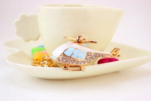 Detail of a golden alloy helicopter keychain with blue enamel and sparkling rhinestones