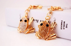 Detailed macro view of two gold frog keychains encrusted with sparkling rhinestones