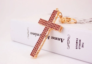 Detailed macro view of a gold-plated cross keychain with sparkling purple rhinestones