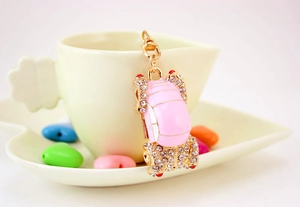 Close-up of pink beetle car keychain with sparkling rhinestones on a ceramic cup