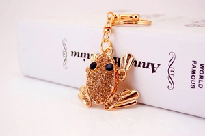 Macro view of gold frog keychain with amber rhinestones on a white book prop