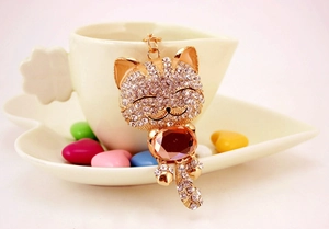 Détail du porte-clés chat porte-bonheur doré avec strass brillants et pierre ambrée facettée