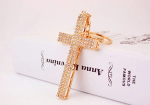 Macro detail of golden cross keychain charm featuring three rows of sparkling crystal rhinestones