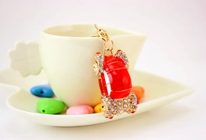 Close-up of red car keychain with rhinestones hanging on a white ceramic cup