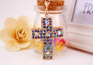 Gros plan d'un porte-clés croix doré orné de strass colorés à effet AB brillant
