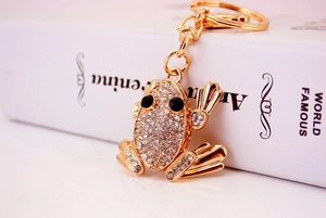 Macro detail of golden frog keychain with white crystals on a white book cover