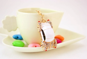 Close-up of white enamel beetle car keychain with crystals hanging on a ceramic cup