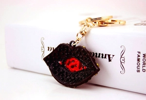 Close-up of stylish lip-shaped keychain with red pattern and golden metal ring