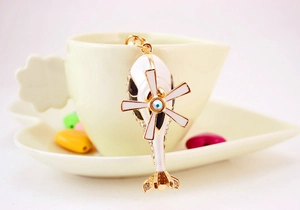 Detailed close-up of a gold helicopter keychain with rhinestones on a coffee cup