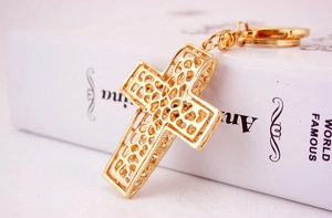 Macro d'un pendentif croix doré avec un design en maille métallique ajourée