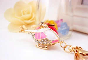 Macro shot of gold helicopter keychain with pink enamel and sparkling rhinestones
