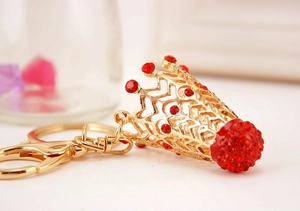 Détail macro du porte-clés couronne avec cadre en métal doré et strass rouges