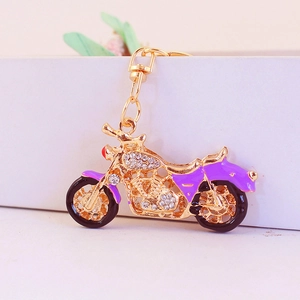 Gold and purple motorcycle keychain with sparkling rhinestones on a white stand