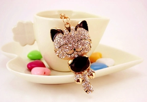 Détail d'un porte-clés chat en cristal suspendu à une tasse à café en céramique