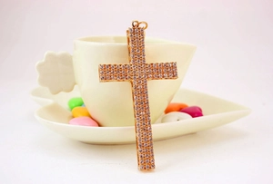 Detailed view of large iced-out gold cross pendant with rhinestones on a cup