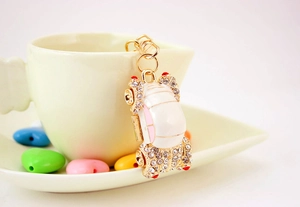 Detailed close-up of a white crystal car keychain with gold plating and lobster clasp