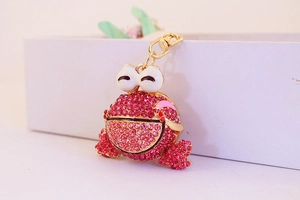 Gros plan d'un porte-clés grenouille avec strass roses et fermoir doré pour sac à main