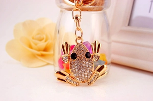 Detailed close-up of golden frog keychain with white rhinestones and lobster clasp