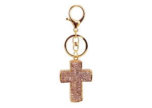 Detailansicht goldener Kreuz Schlüsselanhänger mit rosa Strasssteinen auf weißem Grund