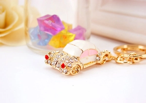 Detailed close-up of a golden car keychain featuring white pink enamel and sparkling crystals