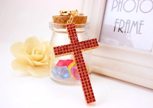 Close-up of gold-plated cross keychain featuring densely set red rhinestones and spring clasp