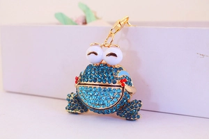 Détail d'un porte-clés grenouille en strass avec cristaux bleus et finition dorée