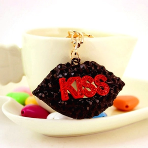 Sparkling black rhinestone lips keychain with red KISS lettering on a white porcelain cup