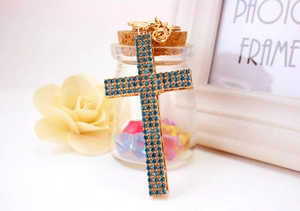 Macro detail of cross keychain with sky blue rhinestones and gold plating on desk