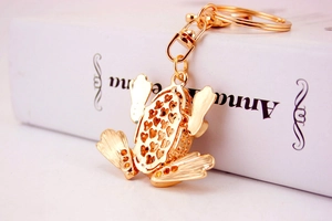 Detailed macro view of the heart-patterned back and gold frog keychain pendant