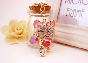 Détail d'un porte-clés chat chanceux avec pierres roses et strass blancs scintillants