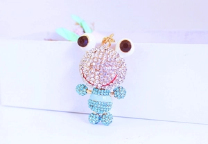 Détail d'un pendentif grenouille doré serti de cristaux scintillants bleus et blancs