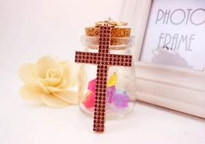 Detailed view of the gold cross keychain with sparkling magenta rhinestones for bags