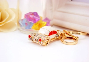Close-up of golden vintage car keychain with white enamel and sparkling rhinestones