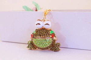 Détail d'un porte-clés grenouille scintillant avec strass verts et fermoir mousqueton doré