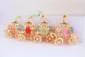 Detailed close-up of golden pumpkin carriage pendants with cat eye stones and rhinestones
