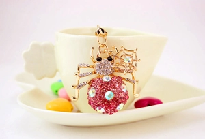 Detail of pink rhinestone spider keychain hanging on a white mug with web charm