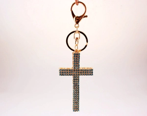 Detail of golden cross keychain with blue crystals and large lobster clasp attachment