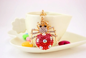 Detail of red and white rhinestone spider keychain hanging on a coffee cup