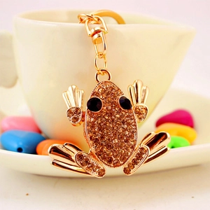 Golden frog keychain with amber rhinestones on a ceramic coffee cup gift setting