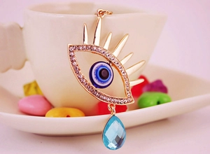 Détail du porte-clés œil maléfique doré avec goutte en cristal bleu et strass scintillants
