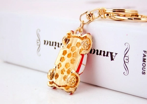 Detail of creative gold car keychain with red enamel accents and lobster clasp fastener