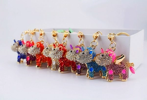 Detailed row of various colored rhinestone unicorn keychains on a white box edge