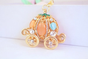 Macro view of gold pumpkin carriage keychain with orange gemstones and sparkling crystals