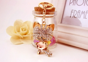 Détail d'un porte-clés chat porte-bonheur doré avec cristaux roses et strass brillants