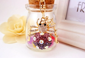 Macro detail of purple rhinestone spider keychain with gold base and cobweb charm
