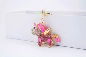 Close-up of pink crystal unicorn keychain with gold wings and sparkling rhinestones