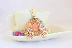 Macro detail of pumpkin carriage keychain with orange cat eye stone and blue crystals